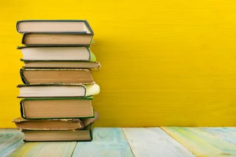 Stack of hardback books, diary on wooden deck table and yellow background. Back Stock Photos
