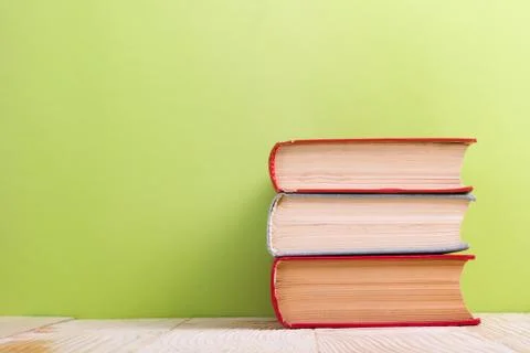 Stack of hardback books, diary on wooden deck table and green background. Back Stock-Fotos