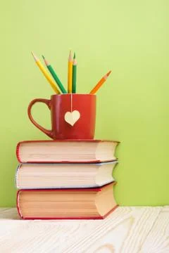 Stack of hardback books, diary on wooden deck table and green background. Back Stock Photos