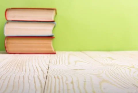 Stack of hardback books, diary on wooden deck table and green background. Back Stock-Fotos