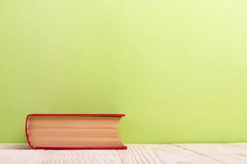 Stack of hardback books, diary on wooden deck table and green background. Back Stock Photos