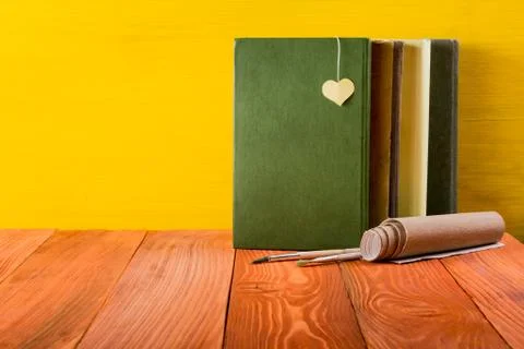 Stack of hardback books, diary on wooden deck table and yellow background. Back Stock-Fotos