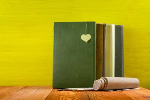 Stack of hardback books, diary on wooden deck table and yellow background. Back Stock Photos