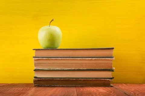 Stack of hardback books, diary on wooden deck table and yellow background. Back Stock Photos