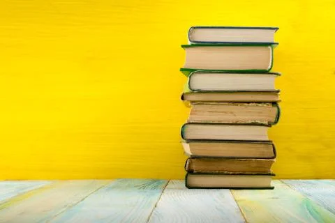 Stack of hardback books, diary on wooden deck table and yellow background. Back Stock-Fotos