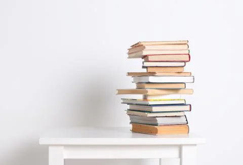 Stack of hardback books on the white table. Search for relevant and necessary Stock Photos
