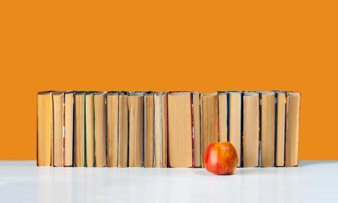 Stack of hardback books on white table with red apple. Books stacking. Back t Stock Photos