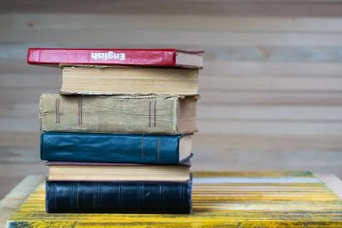 Stack of hardback books on wooden table. English textbook. Stock Photos