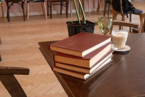 Stack of hardcover books beside coffee on a wooden table in a cafe. Reading.. Fotos Stock