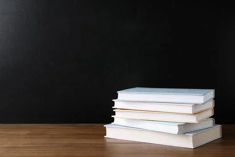 Stack of hardcover books on table against black background, space for text 스톡 사진