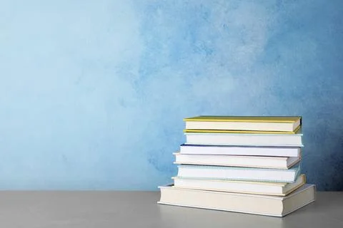 Stack of hardcover books on table against color background, space for text Foto stock