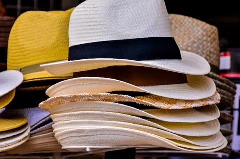 A stack of hats, including a straw hat, a white hat, and a yellow hat Stock Photos
