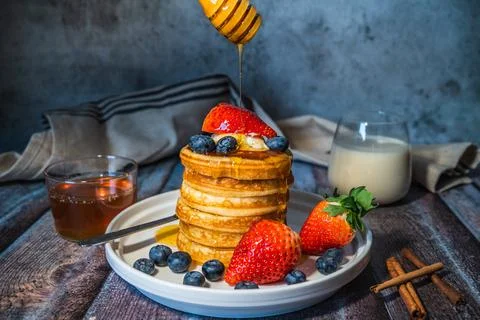 A stack of healthy pancakes with pouring maple syrup from stick, fresh bluebe Stock Photos