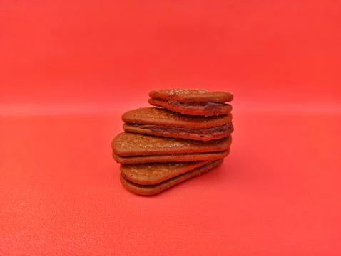 Stack of Heart Shaped Chocolate Sandwich Cookies with Red Filling on Red 스톡 사진