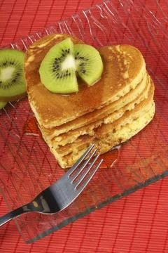 Stack of heart-shaped pancakes with syrup and kiwi fruit on a transparent glass Stock Photos