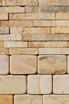 A stack of hewn, rounded yellow sandstone stones in the lower half and rough  Stock Photos