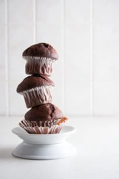 Stack of Homemade chocolate muffins in paper cups on a plate on Kitchen backg Stock Photos