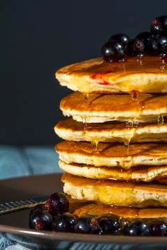 Stack of homemade pancakes with berries and honey on brown plate on rustic ba Stock Photos