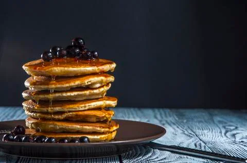 Stack of homemade pancakes with berries and honey on brown plate Stock Photos