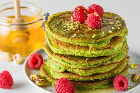 Stack of homemade pancakes with matcha tea, fresh raspberries, pistachios a.. Stock Photos
