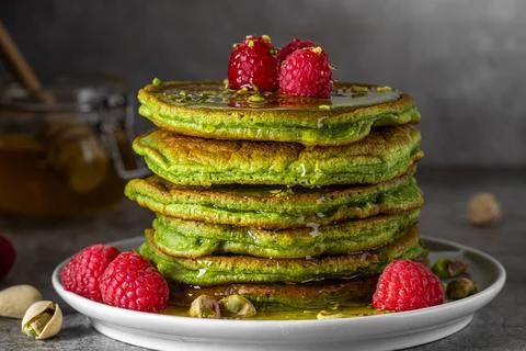 Stack of homemade pancakes with matcha tea, fresh raspberries, pistachios a.. Stock Photos