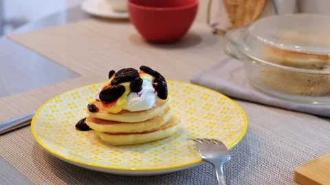 A stack of homemade pancakes on a yellow plate with sour cream, lemon curd, and  Stock Footage 304432891
