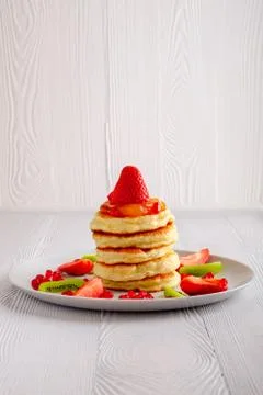 Stack of hot flapjacks served with fresh strawberries and kiwi Foto stock