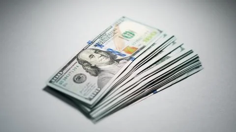 Stack of hundred dollar bills arranged neatly on gray background Stock Photos