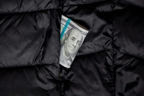 A stack of hundred dollar bills in a black jacket pocket , cash in outerwear Stock Photos