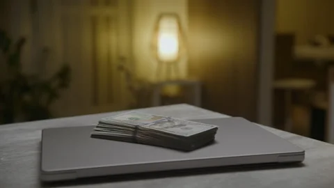 Stack of hundred-dollar bills on closed laptop Stock Footage 302969117