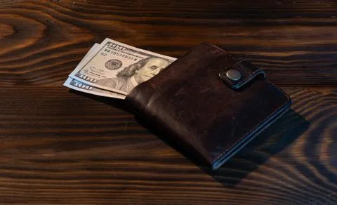 Stack of hundred dollar bills with leather wallet on noble wooden background Stock Photos