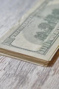A stack of hundred-dollar bills lies on a wooden table, currency exchange, fi Stock Photos