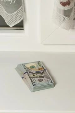 A stack of hundred-dollar bills near the window, a salary. Stock Photos