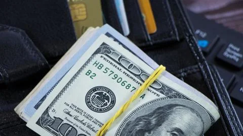 A stack of hundred-dollar bills is on the wallet in the form of a bribe or co Stock Photos