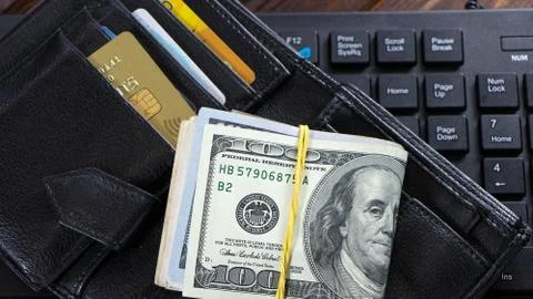A stack of hundred-dollar bills is on the wallet in the form of a bribe or co Stock Photos