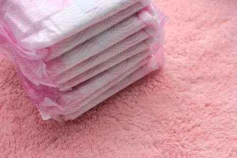 Stack of hygiene feminine menstruation pads on pink towel background. Stock Photos