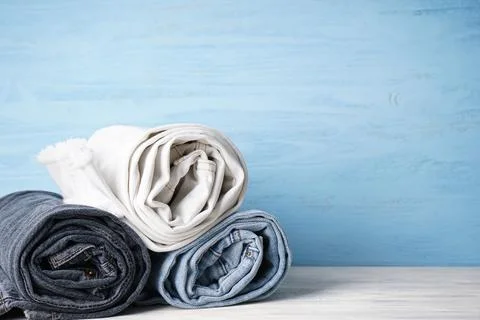 Stack of jeans of various shades, place for text. Jeans are stacked on a wood Stock Photos