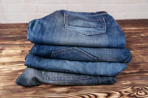 Stack of Jeans on Wooden Table Stock Photos