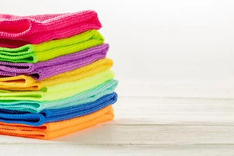 Stack of kitchen microfiber towels in bright colors on a white wooden backg.. Stock Photos