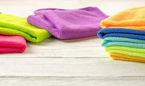 Stack of kitchen microfiber towels in bright colors on a white wooden backgro Stock Photos