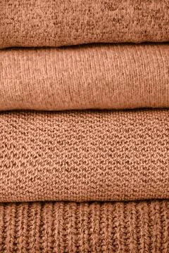 Stack of knit sweaters peach color of the year 2024 Stock Photos