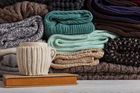 A stack of knitted clothes of different colors and textures, on the table nex Stock Photos
