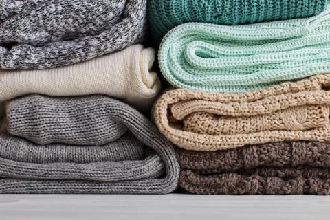 A stack of knitted clothes of different colors and textures. Stock Photos