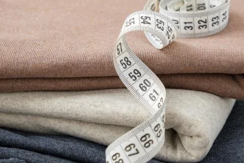Stack of knitted multocolored fabrics closeup and measuring tape. Stock Photos