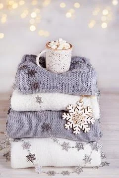 A stack of knitted sweaters or scarves, a cup of cocoa with marshmallows Stock Photos