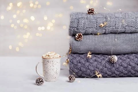 A stack of knitted sweaters or scarves, a cup of cocoa with marshmallows Stock Photos
