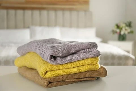 Stack of knitted sweaters on white table indoors Stockfoto's