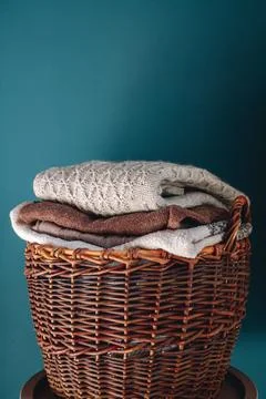 Stack of knitted sweaters on wicker basket. Stock Photos