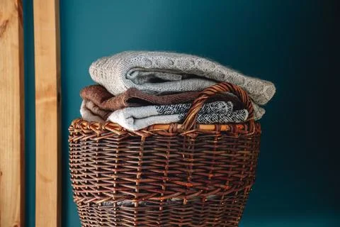 Stack of knitted sweaters on wicker basket. Stock Photos