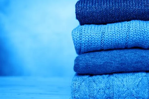 A stack of knitted winter sweaters in several shades of dark blue on concrete Stock Photos